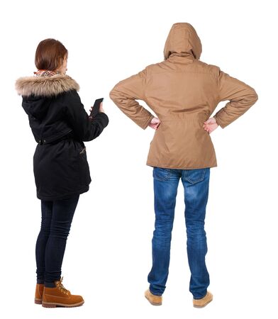 Back view of couple in winter jacket photographed on a mobile phone in winter jacket. beautiful friendly girl and guy together. Rear view people collection. backside view of person. Isolated over white background.の写真素材