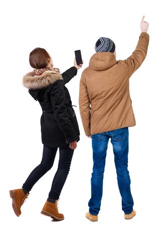 Back view of couple in winter jacket photographed on a mobile phone in winter jacket. beautiful friendly girl and guy together. Rear view people collection. backside view of person. Isolated over white background.の写真素材