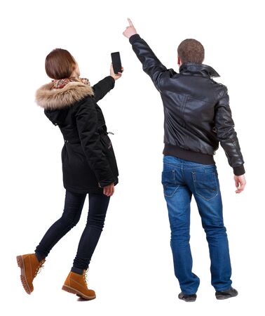 Back view of couple in winter jacket photographed on a mobile phone in winter jacket. beautiful friendly girl and guy together. Rear view people collection. backside view of person. Isolated over white background.の写真素材