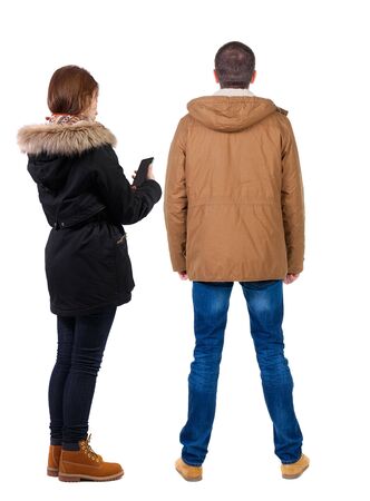 Back view of couple in winter jacket photographed on a mobile phone in winter jacket. beautiful friendly girl and guy together. Rear view people collection. backside view of person. Isolated over white background.の写真素材