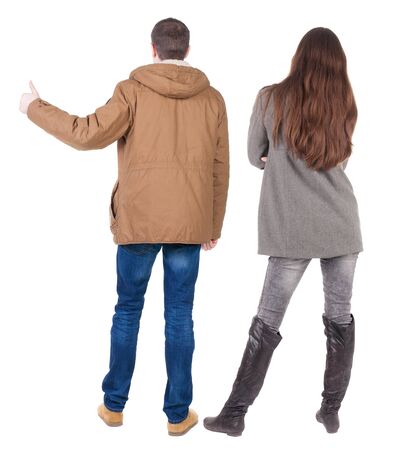 Back view of couple couple in winter jackets showing thumbs up. beautiful friendly girl and guy together. Rear view people collection. backside view of person. Isolated over white background.の写真素材