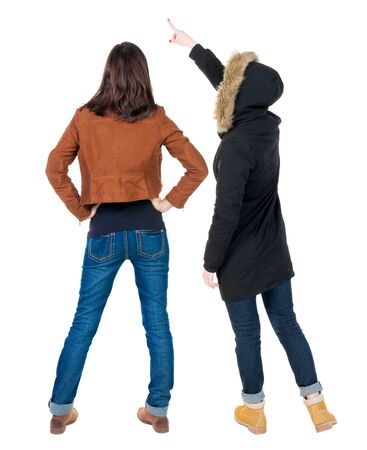 Back view of two pointing young girl in winter jacket. Rear view people collection. backside view of person. beautiful woman friends showing gesture. Rear view. Isolated over white background.の写真素材