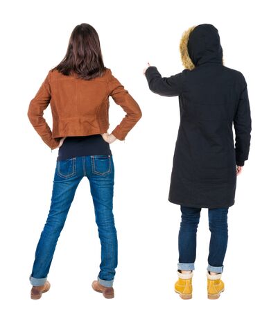 Back view of two pointing young girl in winter jacket. Rear view people collection. backside view of person. beautiful woman friends showing gesture. Rear view. Isolated over white background.の写真素材