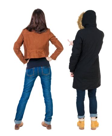 Back view of two pointing young girl in winter jacket. Rear view people collection. backside view of person. beautiful woman friends showing gesture. Rear view. Isolated over white background.の写真素材