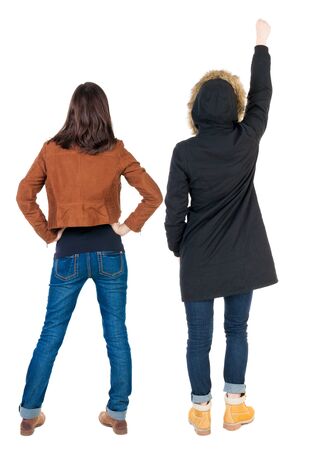Back view of two pointing young girl in winter jacket. Rear view people collection. backside view of person. beautiful woman friends showing gesture. Rear view. Isolated over white background.の写真素材