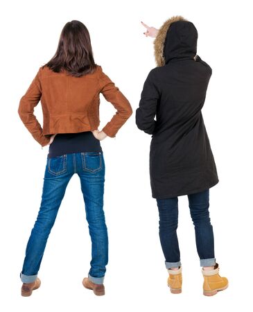 Back view of two pointing young girl in winter jacket. Rear view people collection. backside view of person. beautiful woman friends showing gesture. Rear view. Isolated over white background.の写真素材