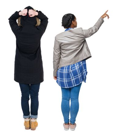Back view of two pointing young girl in winter jacket. Rear view people collection. backside view of person. beautiful woman friends showing gesture. Rear view. Isolated over white background.の写真素材