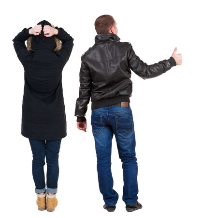 Back view of couple couple in winter jackets showing thumbs up. beautiful friendly girl and guy together. Rear view people collection. backside view of person. Isolated over white background.の写真素材