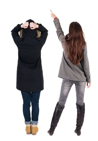 Back view of two pointing young girl in winter jacket. Rear view people collection. backside view of person. beautiful woman friends showing gesture. Rear view. Isolated over white background.の写真素材