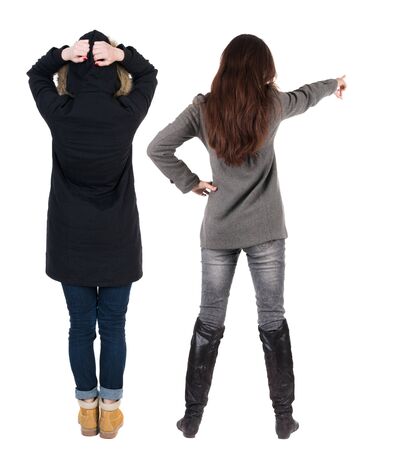 Back view of two pointing young girl in winter jacket. Rear view people collection. backside view of person. beautiful woman friends showing gesture. Rear view. Isolated over white background.の写真素材
