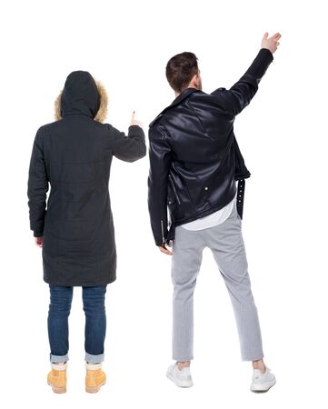 Back view of couple couple in winter jackets pointing. beautiful friendly girl and guy together. Rear view people collection. backside view of person. Isolated over white background.の写真素材