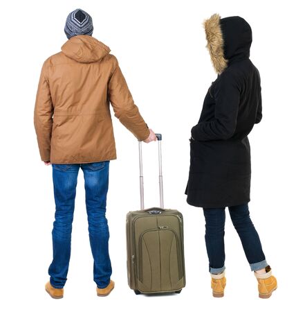 young couple in winter jacket traveling with suitcas. Back view. Rear view people collection. backside view of person. Isolated over white background.の写真素材