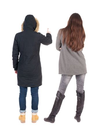 Back view of two pointing young girl in winter jacket. Rear view people collection. backside view of person. beautiful woman friends showing gesture. Rear view. Isolated over white background.の写真素材