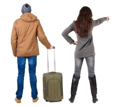 young couple in winter jacket traveling with suitcas. Back view. Rear view people collection. backside view of person. Isolated over white background.の写真素材