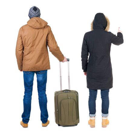 young couple in winter jacket traveling with suitcas. Back view. Rear view people collection. backside view of person. Isolated over white background.の写真素材