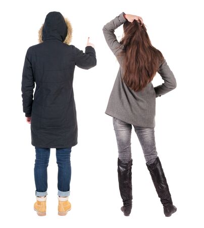 Back view of two pointing young girl in winter jacket. Rear view people collection. backside view of person. beautiful woman friends showing gesture. Rear view. Isolated over white background.の写真素材