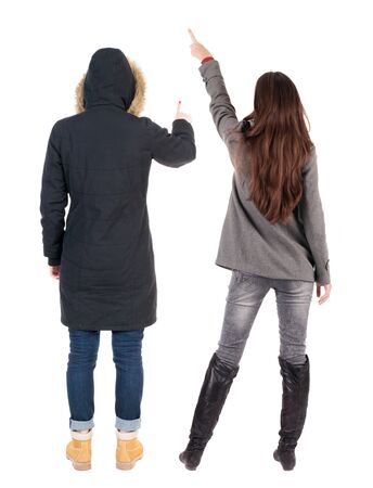 Back view of two pointing young girl in winter jacket. Rear view people collection. backside view of person. beautiful woman friends showing gesture. Rear view. Isolated over white background.の写真素材