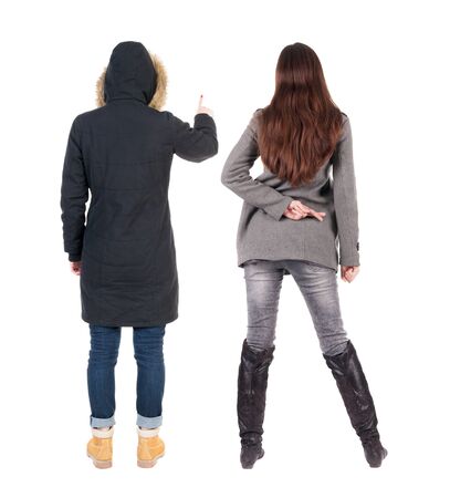 Back view of two pointing young girl in winter jacket. Rear view people collection. backside view of person. beautiful woman friends showing gesture. Rear view. Isolated over white background.の写真素材