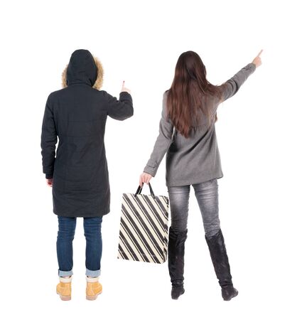 back view of two women with shopping bags in winter jacket. backside view of person. Rear view people collection. Isolated over white background. Two girls with bags stand next procurement.の写真素材