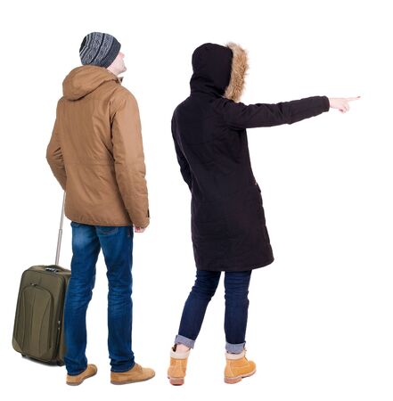 young couple in winter jacket traveling with suitcas. Back view. Rear view people collection. backside view of person. Isolated over white background.の写真素材
