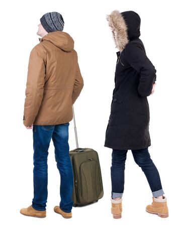 young couple in winter jacket traveling with suitcas. Back view. Rear view people collection. backside view of person. Isolated over white background.の写真素材