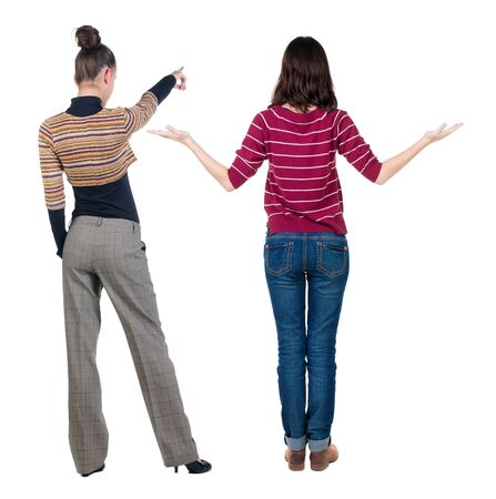 Back view of two pointing young girl in sweater. Rear view people collection. backside view of person. beautiful woman friends showing gesture. Rear view. Isolated over white background.の写真素材