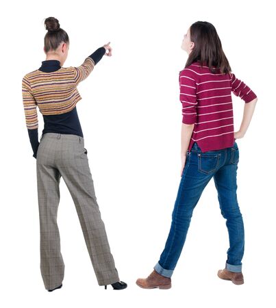 Back view of two pointing young girl in sweater. Rear view people collection. backside view of person. beautiful woman friends showing gesture. Rear view. Isolated over white background.の写真素材