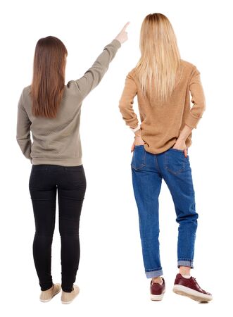 Back view of two pointing young girl in sweater. Rear view people collection. backside view of person. beautiful woman friends showing gesture. Rear view. Isolated over white background.の写真素材