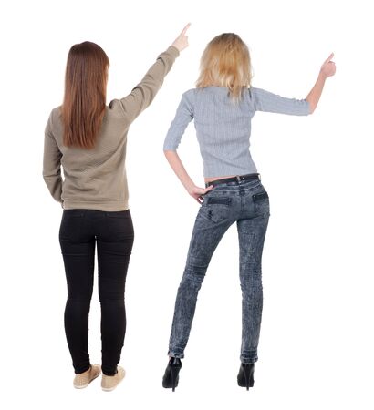 Back view of two pointing young girl in sweater. Rear view people collection. backside view of person. beautiful woman friends showing gesture. Rear view. Isolated over white background.の写真素材