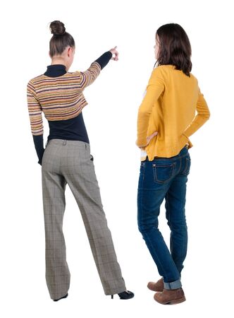 Back view of two pointing young girl in sweater. Rear view people collection. backside view of person. beautiful woman friends showing gesture. Rear view. Isolated over white background.の写真素材