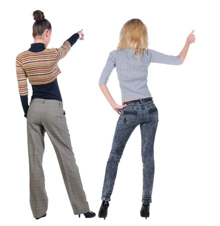 Back view of two pointing young girl in sweater. Rear view people collection. backside view of person. beautiful woman friends showing gesture. Rear view. Isolated over white background.の写真素材