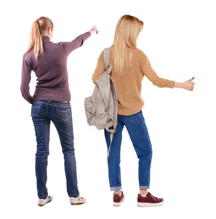 Back view of two pointing young girl in sweater. Rear view people collection. backside view of person. beautiful woman friends showing gesture. Rear view. Isolated over white background.の写真素材