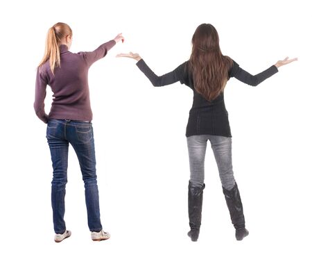 Back view of two pointing young girl in sweater. Rear view people collection. backside view of person. beautiful woman friends showing gesture. Rear view. Isolated over white background.の写真素材