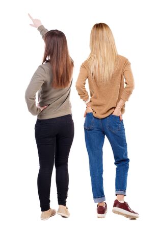 Back view of two pointing young girl in sweater. Rear view people collection. backside view of person. beautiful woman friends showing gesture. Rear view. Isolated over white background.の写真素材