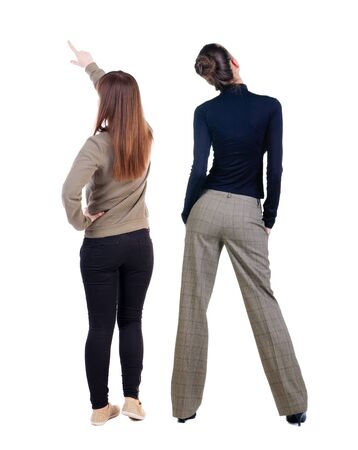 Back view of two pointing young girl in sweater. Rear view people collection. backside view of person. beautiful woman friends showing gesture. Rear view. Isolated over white background.の写真素材