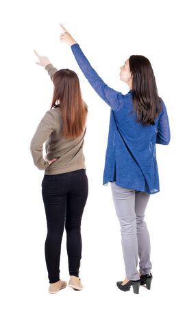 Back view of two pointing young girl in sweater. Rear view people collection. backside view of person. beautiful woman friends showing gesture. Rear view. Isolated over white background.の写真素材