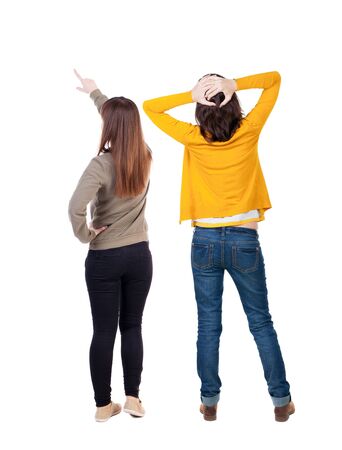 Back view of two pointing young girl in sweater. Rear view people collection. backside view of person. beautiful woman friends showing gesture. Rear view. Isolated over white background.の写真素材