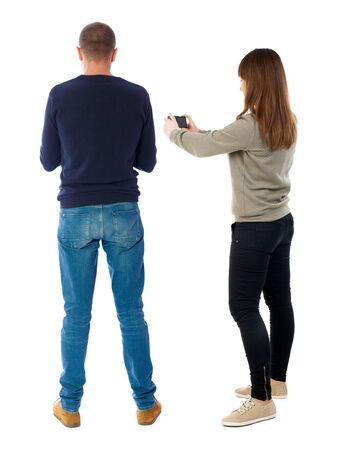 Back view of couple in sweater with mobile phone. beautiful friendly girl and guy together. Rear view people collection. backside view of person. Isolated over white background.の写真素材