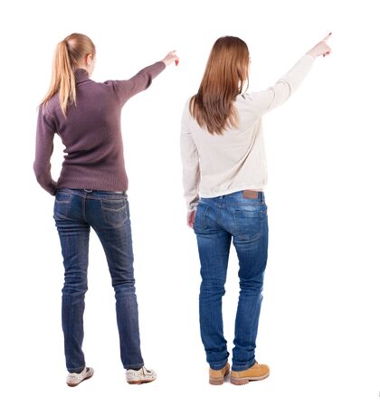 Back view of two pointing young girl in sweater. Rear view people collection. backside view of person. beautiful woman friends showing gesture. Rear view. Isolated over white background.の写真素材