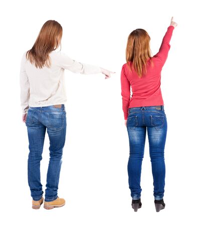 Back view of two pointing young girl in sweater. Rear view people collection. backside view of person. beautiful woman friends showing gesture. Rear view. Isolated over white background.の写真素材