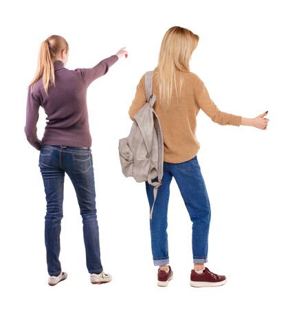 Back view of two pointing young girl in sweater. Rear view people collection. backside view of person. beautiful woman friends showing gesture. Rear view. Isolated over white background.の写真素材