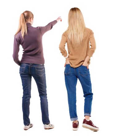 Back view of two pointing young girl in sweater. Rear view people collection. backside view of person. beautiful woman friends showing gesture. Rear view. Isolated over white background.の写真素材