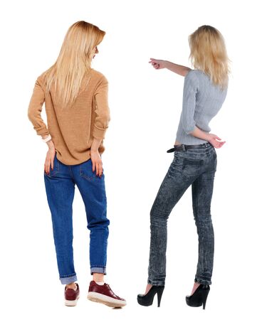 Back view of two pointing young girl in sweater. Rear view people collection. backside view of person. beautiful woman friends showing gesture. Rear view. Isolated over white background.の写真素材