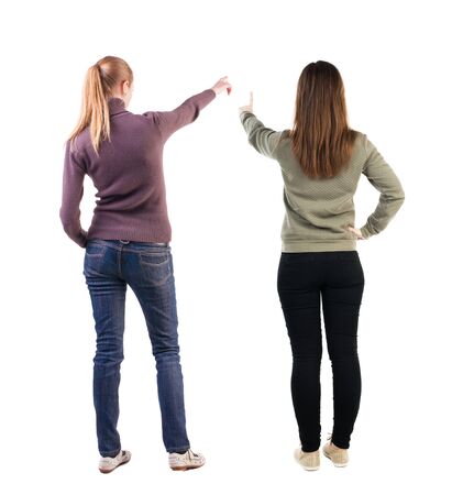 Back view of two pointing young girl in sweater. Rear view people collection. backside view of person. beautiful woman friends showing gesture. Rear view. Isolated over white background.の写真素材