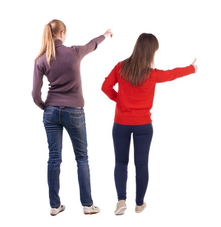 Back view of two pointing young girl in sweater. Rear view people collection. backside view of person. beautiful woman friends showing gesture. Rear view. Isolated over white background.の写真素材