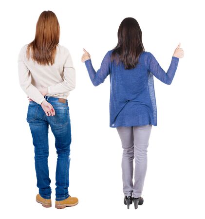 Back view of two young girl in sweater showing thumb up. Rear view people collection. backside view of person. beautiful woman friends showing gesture. Rear view. Isolated over white background.の写真素材