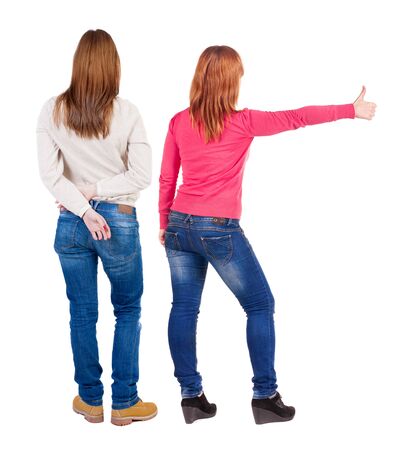 Back view of two young girl in sweater showing thumb up. Rear view people collection. backside view of person. beautiful woman friends showing gesture. Rear view. Isolated over white background.の写真素材