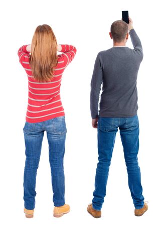 Back view of couple in sweater with mobile phone. beautiful friendly girl and guy together. Rear view people collection. backside view of person. Isolated over white background.の写真素材