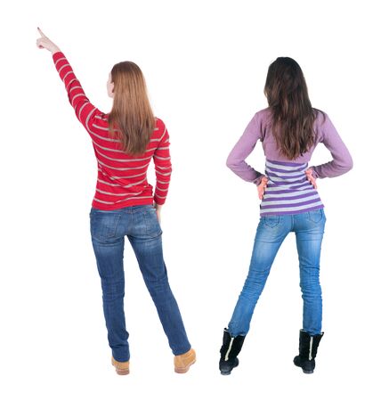 Back view of two pointing young girl in sweater. Rear view people collection. backside view of person. beautiful woman friends showing gesture. Rear view. Isolated over white background.の写真素材
