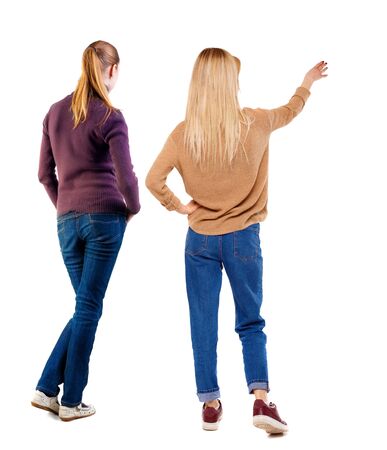 Back view of two pointing young girl in sweater. Rear view people collection. backside view of person. beautiful woman friends showing gesture. Rear view. Isolated over white background.の写真素材